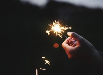 Close-up of hand holding sparkler at night