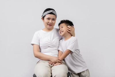 Smiling boy sitting against white background