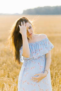 Tender pregnant woman walk in a field. lady in blue dress. relax time. woman is waiting for a baby