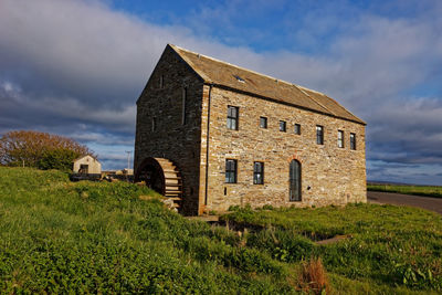 Old house on field against sky