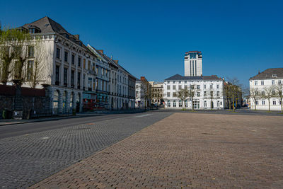 Street amidst buildings against clear blue sky