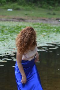 Rear view of woman standing on lake