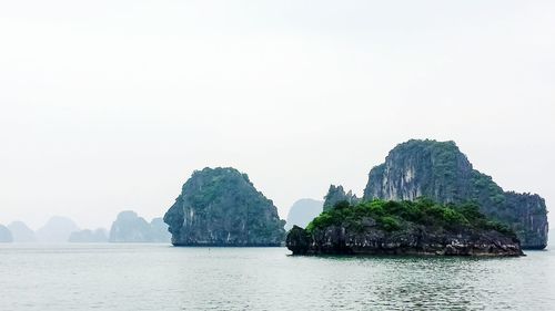 Rock formations by sea against clear sky