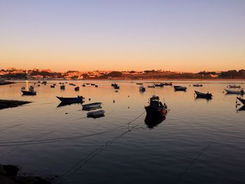 Boats moored on sea against sky during sunset