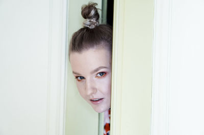 Close-up portrait of woman with make-up looking through door