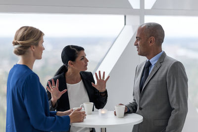 Businessman and businesswomen talking while drinking coffee