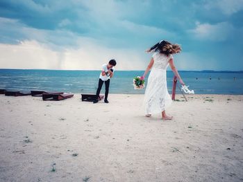 Friends enjoying at beach against sky