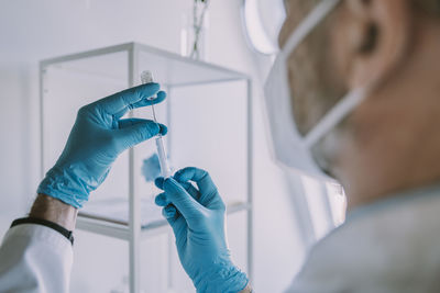 Doctor taking vaccination in syringe while standing at examination room during covid-19