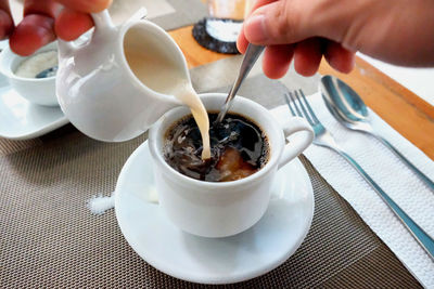 Cropped hand of person preparing coffee on table