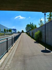 Empty road by bridge against sky