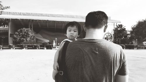 Rear view of boys standing against sky