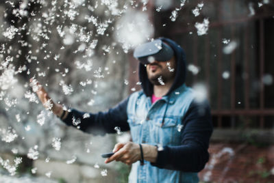 Young man using virtual reality simulator during snowfall