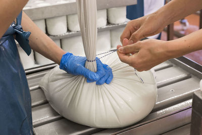 Coworkers tying sack with string at factory