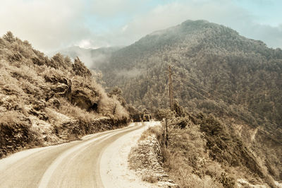 Road leading towards mountains against sky