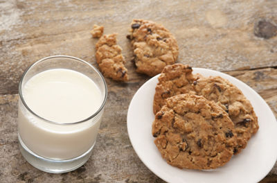 High angle view of cookies by milk in glass on table