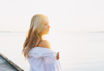 Young woman looking at sea against sky