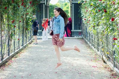 Full length of happy woman jumping on garden path