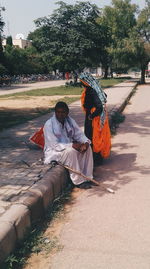 People sitting on road against trees