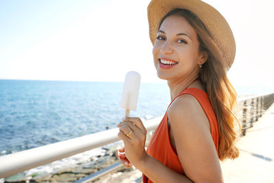 Portrait of laughing brazilian woman eating a lemon popsicle looking at the camera on summer