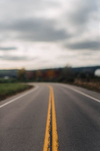 Surface level of empty road against cloudy sky