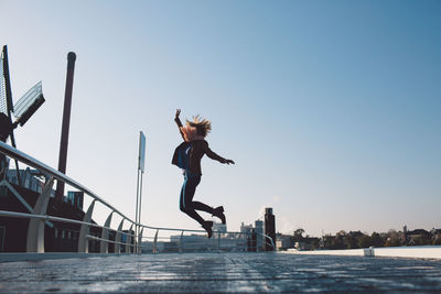 Full length of woman jumping against clear sky