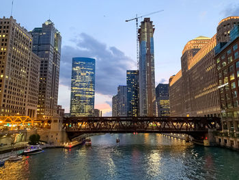 Bridge over river by buildings against sky in city