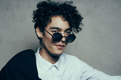 Portrait of young man wearing sunglasses against wall