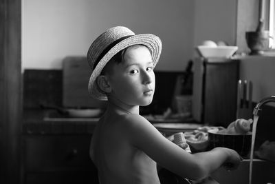 Portrait of boy standing by sink in kitchen at home