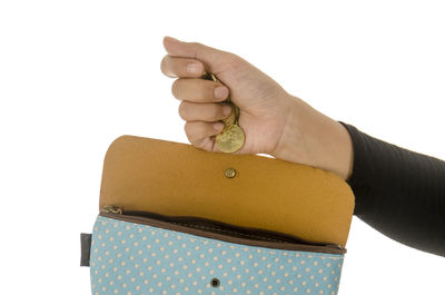 Close-up of hand holding hat against white background