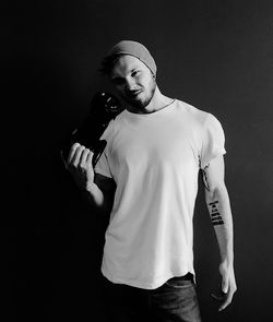 Portrait of young man standing against black background