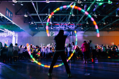 Man spinning illuminated lighting equipment at music concert