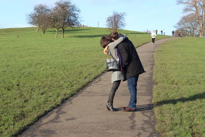 Full length of couple embracing on footpath in park