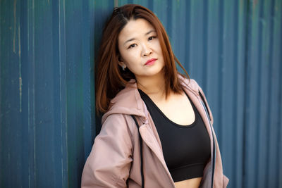 Portrait of young woman standing against yellow wall