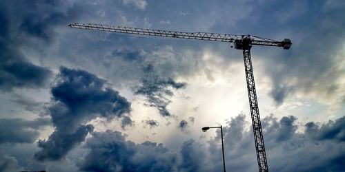 Low angle view of silhouette crane against sky