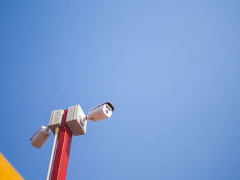 Low angle view of telephone pole against clear blue sky