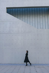 Side view of woman walking on snow covered building