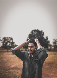 Young man standing on field against clear sky