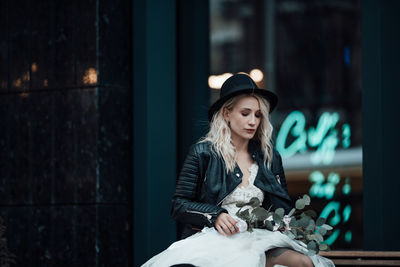 Young woman looking away while sitting outdoors