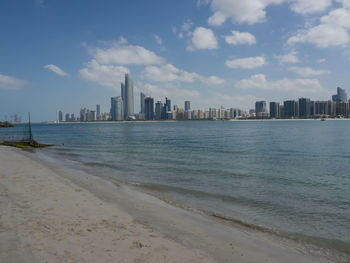 Sea by modern buildings against sky in city