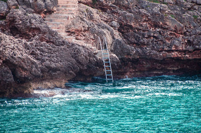 Scenic view of sea and rock formation with ladder