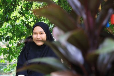 Portrait of woman standing against plants