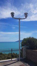 Street light by sea against sky