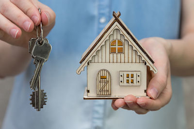 Midsection of woman holding model home and house keys