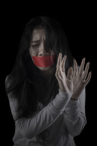Scared woman with duct tape against black background