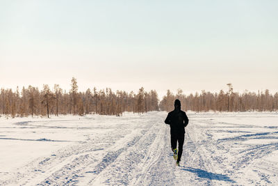 Sporty man in sportswear running in a winter park, copy space. a runner trains outdoors