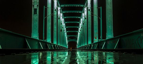 Illuminated bridge over river in city at night