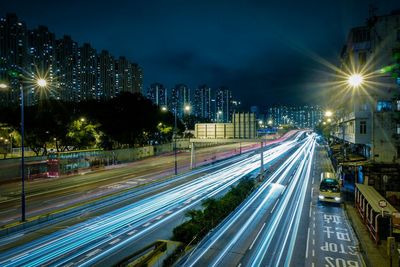 Light trails on highway in city against sky at night