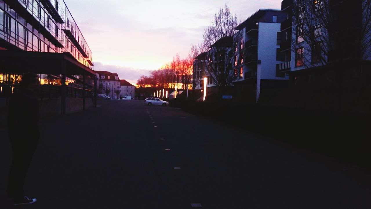 building exterior, architecture, built structure, sunset, city, street, sky, the way forward, building, transportation, silhouette, residential building, city life, residential structure, road, dusk, sunlight, outdoors, car, diminishing perspective