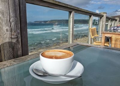 Close-up of coffee on table by sea against sky