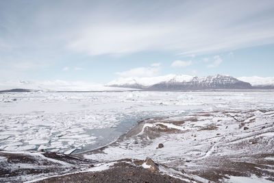 Scenic view of snowcapped mountains by sea against sky